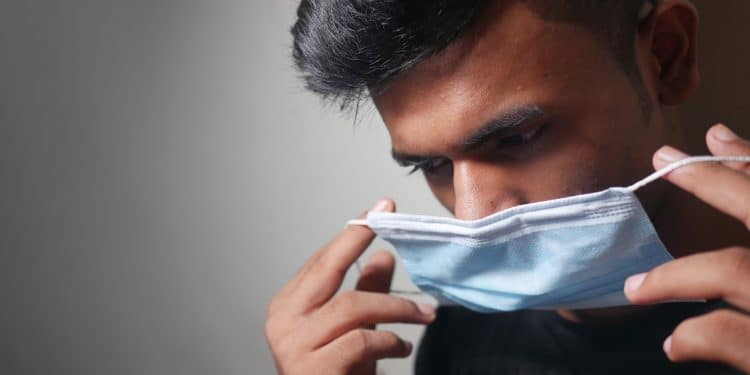 man in black shirt covering his face with white textile