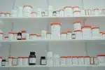 a shelf filled with lots of white and orange medicine bottles