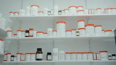 a shelf filled with lots of white and orange medicine bottles