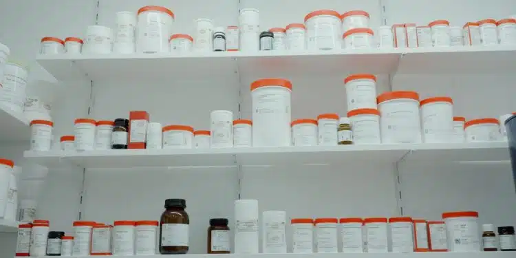 a shelf filled with lots of white and orange medicine bottles